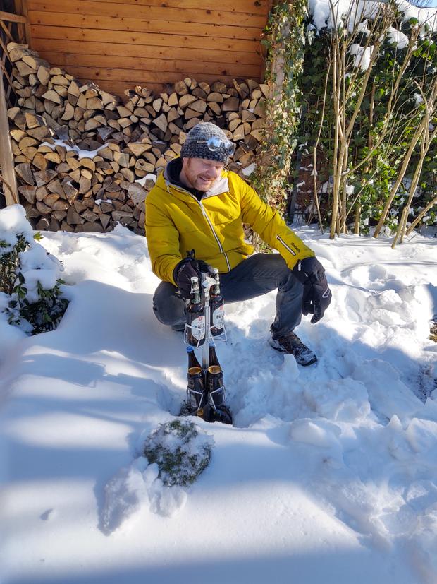 A man pulls a BEERSAFE out of the ground in the snow