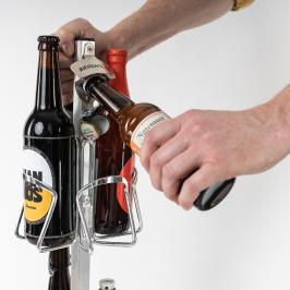 Eine Person öffnet Kronkorken einer Bierflasche am Gerüst des Biersafes