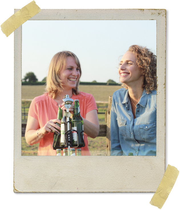 Two women are laughing and opening a beer on the scaffold of a BIERSAFE
