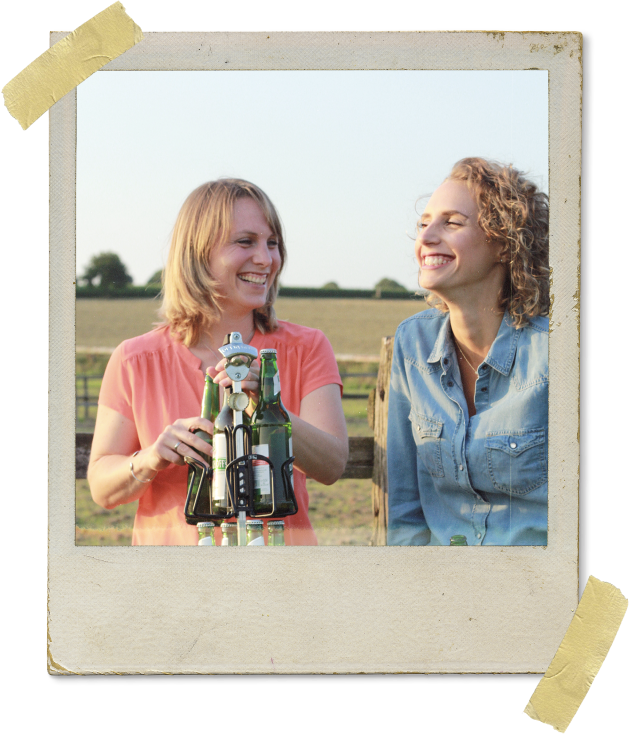 Zwei Frauen lachen und öffnen ein Bier am Gerüst des BIERSAFEs