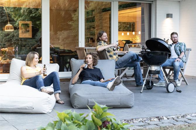 The BIERSAFE team sits together on the terrace barbecuing and drinking beer.